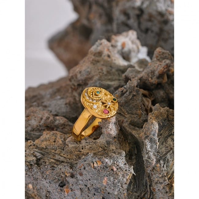 Gold ring with gemstones on a textured stone surface